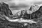 portfolio stock photography | Yosemite Valley and Bridalveil Falls from Tunnel View, Yosemite National Park, California, USA, Image ID AMERICAN-SOUTHWEST-BW-0001. Black and white photo of the Yosemite Valley and Bridalveil Falls from Tunnel View early in the morning. Snow covered peaks, mountains and trees and morning fog is laying in the valley. Tunnel View, within Yosemite National Park, is a viewpoint on State Route 41 located directly east of the Wawona Tunnel as one enters Yosemite Valley from the South. The view looks east into Yosemite Valley including the southwest face of El Capitan, Half Dome, and Bridalveil Falls. This is, to many, the first views of the popular attractions in Yosemite. Many cars stop right outside of the tunnel to take pictures and absorb the visual aesthetics.