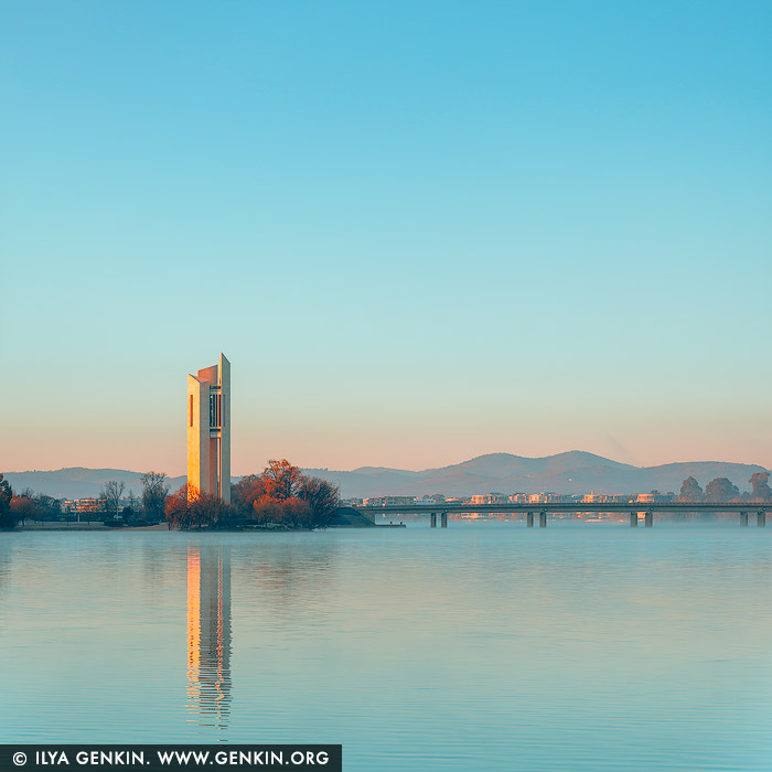 australia stock photography | National Carillon at Sunrise, Canberra, Australian Capital Territory (ACT), Australia. At sunrise, the National Carillon on Queen Elizabeth II Island (formerly known as Aspen Island) emerges in a cinematic palette of teal and orange. The tower's angular Brutalist lines reflect the dawn's glow, standing tall at 50 meters above Lake Burley Griffin. Gifted by Britain in 1970 to commemorate Canberra's 50th anniversary, its 57 bronze bells, cast by John Taylor & Co., span nearly five octaves. The 2019 addition of the Ngunnawal Bell honors the region's Indigenous heritage. As the sun rises, the Carillon's silhouette and resonant chimes offer a serene start to the day.