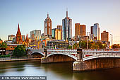 australia stock photography | Melbourne, Princes Bridge and Flinders Street Station at Sunrise, Southbank, Melbourne, Victoria, Australia, Image ID AU-MELBOURNE-0030. Named in honour of HRH the Prince of Wales, later King Edward VII, Princes Bridge is dominated by squat half columns, resting on giant piers, contrasting with its delicate iron girder piers. The bridge's decoration, in typical Victorian era style, includes mouldings and balustrades along the top of the bridge and lamp standings crowning the giant half columns, with the coats of arms of the municipal councils who contributed towards the cost of construction decorating the spandrels. The bridge's abutments, piers and wing walls are made of bluestone quarried from Footscray. The present bridge was built in 1888 and is listed on the Victorian Heritage Register.