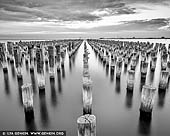 australia stock photography | Princes Pier at Port Phillip Bay, Melbourne, Victoria, Australia, Image ID AU-MELBOURNE-0038. The 580 metre long Princes Pier was built between 1912 and 1915 and was the third major pier constructed at Port Melbourne. Together with the adjacent Station Pier, it served as a major passenger and cargo terminal in the twentieth century until its closure in 1989. From completion in 1915 until 1969 it was also a major arrival point for new migrants, particularly during the post-war period. In addition to a pier, there was a gatehouse and barriers, terminal building, amenities rooms, goods lockers, ablution blocks, railway sidings and passenger gangways. From opening the pier was linked by rail to the Port Melbourne railway line. With the containerisation boom the pier became unused, being closed to public access in the early 1990s due to the poor timber condition, and squatters caused a fire in the late 1990s that destroyed the store structures. Restored and modified to allow safe public access, Princes Pier reopened in 2011. It was known as the New Railway Pier until renamed Prince's Pier after the Prince of Wales (later Edward VIII) who visited Melbourne in May 1920.