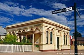 australia stock photography | Wentworth Post Office, Wentworth, New South Wales (NSW), Australia, Image ID AU-WENTWORTH-0002. Wentworth Post Office located on the corner of Sandwych and Darling Streets near ANZAC Memorial. An ornate single storey brick structure displaying a series of double round headed windows. These windows are hooded with stilted arches with keystones and divided by doric style pilasters. The building corners and entranceway are bordered with tall doric pilasters. The entranceway is highlighted by a large romanesque arch with keystone surrounding a moulded panel. A plain parapet wall sits above a mouldered string course adorned with dentils. A side awning is supported by chamfered posts and decorated with a timber criss-cross frieze. The post office is one of the most prominent structures in Wentworth and importantly compliments the surrounding heritage items of Darling Street.