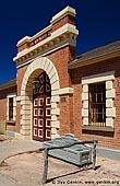 australia stock photography | Old Wentworth Gaol, Wentworth, New South Wales (NSW), Australia, Image ID AU-WENTWORTH-0011. The Old Wentworth Gaol is a small single storey brick gaol with bluestone trim. The entrance is highlighted by a large panelled doorway set in an arch surrounded by stone quoins. The front parapet has a stone corbel trim. The large square windows are surrounded by bluestone quoins. The roof is tiled with slate. The structure is a typical small gaol of the late Victorian period similar to others built in Hay and Gunnedeh. Probably the best example in New South Wales.