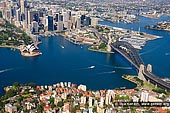 australia stock photography | Sydney City Aerial View, Sydney, NSW, Australia, Image ID AU-SYDNEY-0010. Aerial view photo of Sydney Cove at the Foot of the City. The Sydney Opera House stands out boldly on the harbour. The Royal Botanic Gardens and Government House are behind it and the Harbour Bridge crossing the Sydney Harbour takes you to North Sydney and beyond.