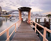 australia stock photography | Lavender Bay Wharf at Dawn, McMahons Point, Sydney, NSW, Australia, Image ID AU-SYDNEY-0025. Soft pastel hues at sunrise the sky over the Lavender Bay Wharf on the McMahons Point in Sydney, NSW, Australia with the Sydney Harbour Bridge in the distance.