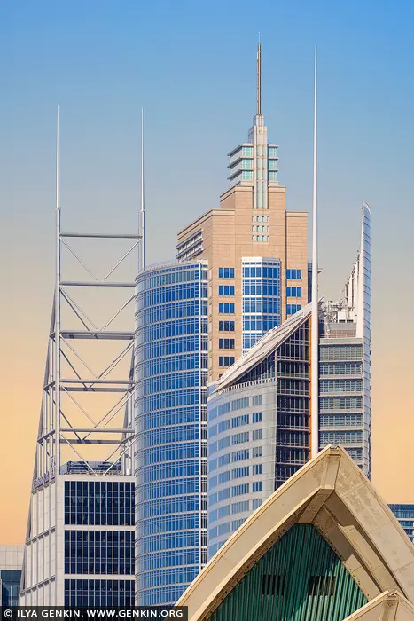 australia stock photography | Sunrise Geometry: Skyscrapers and Shells in Sydney, Sydney, New South Wales (NSW), Australia. As dawn breaks over Sydney, a symphony of architectural forms awakens in warm, golden light. The city's modern skyline rises like a sculptural ensemble - sleek glass towers, sharp lines, and metal frameworks converging in perfect harmony. In the foreground, a subtle glimpse of the iconic Sydney Opera House hints at the city's timeless soul, contrasting with the futuristic precision of its vertical neighbours. This image captures not just buildings, but a moment of balance between heritage and progress, softness and structure. The pastel sky adds serenity to the urban complexity, making it a striking yet calming piece - ideal for a contemporary living room, stylish office, or minimalist interior seeking a touch of sophistication.