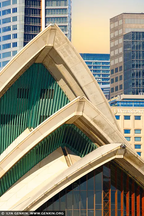 australia stock photography | Architectural Harmony: Sydney Opera House at Sunrise, Sydney, New South Wales (NSW), Australia. At sunrise, the sculptural sails of the Sydney Opera House glow in soft, golden light - their rhythmic curves rising gracefully against a backdrop of sharp-edged modern towers. This close-up reveals the intricate textures and rich interplay of geometry, where the organic meets the architectural. The green-tiled shells shimmer with quiet elegance, framed by the grid-like patterns of Sydney's urban skyline, capturing a moment where art, culture, and design coexist in perfect balance. This striking composition invites reflection and admiration - ideal for adding depth and sophistication to any contemporary space, from a minimalist living room to a stylish office.