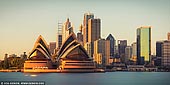 australia stock photography | Opera House and Sydney City at Sunrise, Kirribilli, Sydney, New South Wales (NSW), Australia, Image ID AU-SYDNEY-OPERA-HOUSE-0040. A shot from Kirribilli on the North Shore looking across harbour to Sydney Opera House and the city, captured early morning with the sun hitting the CBD skyline and reflecting beautiful yellow and orange colours from the glass windows. The photo has a great 2:1 ratio, which makes it stand out from the usual photograph.