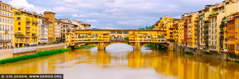 italy stock photography | Timeless Charm of Ponte Vecchio in Soft Light, Florence, Tuscany, Italy. Under a canopy of soft, cloud-strewn skies, the Ponte Vecchio stretches gracefully across the golden-tinted Arno River, glowing with centuries of Florentine history. The rich yellows and warm ochres of the historic buildings lining the bridge and riverbanks seem to hum with quiet elegance. In this panoramic composition, the timeless architecture draws the eye toward the heart of Renaissance Florence - a place where artisans once traded gold and dreams. The gentle light, mirrored in the calm waters below, evokes a feeling of warmth and nostalgia. This artwork brings a refined, European touch to any interior - ideal for adding character and cultured beauty to a living space or office.