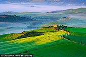 Sun-Kissed Serenity in Val d'Orcia - Fine art print of Pienza, Val d'Orcia, Tuscany, Italy - As sunrise gently unfurls across the rolling hills of Val d'Orcia, morning fog lingers in soft ribbons, cloaking the valleys in mystery and calm. The golden light caresses fields of emerald green, highlighting graceful lines etched into the land by centuries of cultivation. A winding cypress-lined road leads to a quiet farmhouse - a beacon of stillness amid the poetic landscape. This is Tuscany at its most intimate: peaceful, timeless, and bathed in a painterly glow. A piece like this invites slow mornings and thoughtful pauses, perfect for adding warmth and tranquility to any home, studio, or creative space. - Image ID: ITALY-TUSCANY-0016