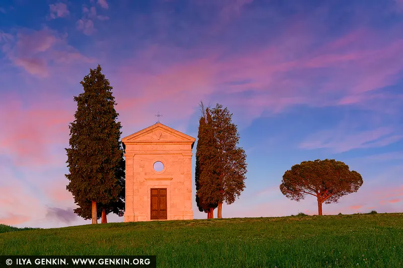 Twilight Grace: Madonna di Vitaleta Chapel at Sunset - Fine art print of Pienza, Val d'Orcia, Tuscany, Italy - Bathed in the delicate hues of a Tuscan sunset, the Cappella della Madonna di Vitaleta stands quietly amid rolling green hills - a vision of serenity and grace. Flanked by cypress trees and a lone umbrella pine, this small stone chapel seems to glow from within, its soft façade catching the last light of day beneath a sky painted in lavender and rose. A place of pilgrimage and timeless beauty, this sacred site near San Quirico d'Orcia is more than architecture - it's a moment of stillness, captured in color and light. Perfect for bringing warmth, spirituality, and a sense of poetic calm to any interior. - Image ID: ITALY-TUSCANY-0018
