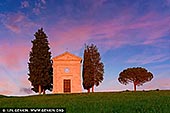 Twilight Grace: Madonna di Vitaleta Chapel at Sunset - Fine art print of Pienza, Val d'Orcia, Tuscany, Italy - Bathed in the delicate hues of a Tuscan sunset, the Cappella della Madonna di Vitaleta stands quietly amid rolling green hills - a vision of serenity and grace. Flanked by cypress trees and a lone umbrella pine, this small stone chapel seems to glow from within, its soft façade catching the last light of day beneath a sky painted in lavender and rose. A place of pilgrimage and timeless beauty, this sacred site near San Quirico d'Orcia is more than architecture - it's a moment of stillness, captured in color and light. Perfect for bringing warmth, spirituality, and a sense of poetic calm to any interior. - Image ID: ITALY-TUSCANY-0018