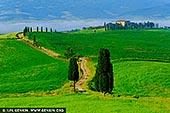 Elysian Path. Morning Light over Tuscany's Gladiator Road - Fine art print of Pienza, Val d'Orcia, Tuscany, Italy - Bathed in golden morning light, this sweeping view of Val d'Orcia captures the legendary cypress-lined path near Pienza - immortalised as the 'Gladiator Road'. Winding gently through emerald fields, the road leads the eye to a distant farmhouse crowned with stately cypress trees, evoking memories of Maximus's dreamlike homecoming in Gladiator. The velvety hills, cloaked in vibrant green, unfold like a Renaissance painting, with mist gently resting on the horizon beneath soft blue mountains. This image is not just a landscape, but a moment of serenity and cinematic reverence - a timeless piece ideal for spaces seeking calm, warmth, and a touch of Tuscan romance. - Image ID: ITALY-TUSCANY-0020
