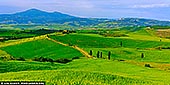 Tuscany's Eternal Dream. The Gladiator Road Unfolds - Fine art print of Pienza, Val d'Orcia, Tuscany, Italy - Sweeping across the undulating hills of Val d'Orcia, this breathtaking panorama captures the iconic 'Gladiator Road' in all its cinematic grandeur. The serpentine path, lined with sentinel cypress trees, leads the eye toward a golden farmhouse nestled in the distance - a scene so timeless and serene, it feels lifted from a dream. Beneath a soft sky and against the majestic backdrop of Monte Amiata, the landscape radiates lush greens and rich light, embodying the soul of the Tuscan countryside. This photograph invites stillness and wanderlust - a perfect centrepiece for interiors that celebrate beauty, heritage, and quiet inspiration. - Image ID: ITALY-TUSCANY-0021