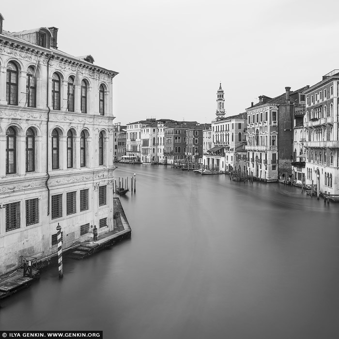 italy stock photography | Venice Grand Canal, Study 2, Venice, Veneto, Italy. Stillness in motion. Viewed from the timeless vantage of Ponte di Rialto, this black and white long exposure captures the Grand Canal in a state of suspended silence. The blurred water flows like fog through the architectural canyon, soft and weightless, while the surrounding buildings rise in perfect clarity - their lines more pronounced in monochrome. Without color, Venice feels eternal, its ornate facades etched like memories in stone. The near-empty sky, barely touched by clouds, only deepens the sense of calm and permanence in this quiet slice of daylight Venice.