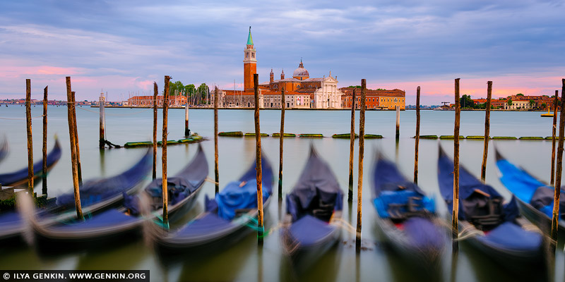 italy stock photography | Church of San Giorgio Maggiore and Venetian Gondolas at Sunrise, Venice, Veneto, Italy. As dawn breaks over Venice, the sky ignites in a symphony of warm hues - rose gold, tangerine, and lavender - casting a soft glow across the still waters of the lagoon. From Riva degli Schiavoni, the scene opens wide: classic Venetian gondolas gently sway in the foreground, their silhouettes etched against the shimmering reflections. Across the water, the majestic Church of San Giorgio Maggiore rises in quiet elegance, its Palladian facade kissed by the first light. This slightly panoramic view captures the soul of Venice in a single, fleeting moment - timeless, romantic, and utterly serene.