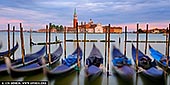  stock photography | Church of San Giorgio Maggiore and Venetian Gondolas at Sunrise, Venice, Veneto, Italy, Image ID ITALY-VENICE-0004. As dawn breaks over Venice, the sky ignites in a symphony of warm hues - rose gold, tangerine, and lavender - casting a soft glow across the still waters of the lagoon. From Riva degli Schiavoni, the scene opens wide: classic Venetian gondolas gently sway in the foreground, their silhouettes etched against the shimmering reflections. Across the water, the majestic Church of San Giorgio Maggiore rises in quiet elegance, its Palladian facade kissed by the first light. This slightly panoramic view captures the soul of Venice in a single, fleeting moment - timeless, romantic, and utterly serene.