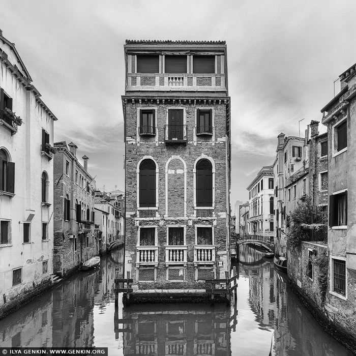 italy stock photography | Venice Canals and Streets, Study 1, Venice, Veneto, Italy. In this striking black-and-white capture, a narrow Venetian palazzo rises like a surreal stage set, perfectly framed between two quiet canals. The stark symmetry and elegant arches of the building's facade contrast beautifully with the soft ripples below, while the surrounding alleyways curve gently out of view, hinting at the labyrinthine charm of Venice. Stripped of color, the scene feels timeless - its textures and geometry more pronounced, the silence almost audible. This image encapsulates the poetic stillness of Venice, where history, architecture, and water intertwine in a dreamlike balance.