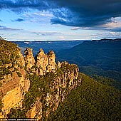 landscapes stock photography | The Three Sisters, Echo Point, Katoomba, Blue Mountains, NSW, Australia, Image ID THREE-SISTERS-BLUE-MOUNTAINS-0004. Fine art landscape photography of The Three Sisters in square format. The Three Sisters are an icon of the Blue Mountains and NSW. These three pillars can be seen from the viewing platform at Echo Point in Katoomba, Blue Mountains, NSW, Australia. There is a fascinating Aboriginal dream-time legend that explains the story of the sisters and how they got there: The story tells of three sisters who were part of the Katoomba tribe who lived in the Jamison Valley. The three young women, Meehni, Wimblah and Gunnedoo had fallen in love with three boys (who were also brothers) from the Nepean tribe. However they weren't able to marry because of tribal law. The brothers upset by this decided to capture the three sisters, which started a battle between the two tribes. A witchdoctor from the Katoomba tribe took it upon himself to protect the sisters from harm, but turning them into stone for protection. He was killed during the battle so he was unable to turn them back to flesh like he planned to, after the battle was over. The sisters are still beautiful in their rock formation and remain there as a reminder of the battle that took place between the two tribes.