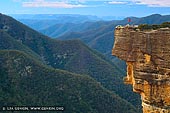 landscapes stock photography | Kanangra Walls, Kanangra-Boyd National Park, New South Wales (NSW), Australia, Image ID AU-KANANGRA-BOYD-NP-0002. Woman is standing on the edge of the Kanangra Walls cliffs in the Kanangra-Boyd National Park in New South Wales (NSW), Australia overlooking canyons and mountain ranges covered in blue mist from eucalyptus.