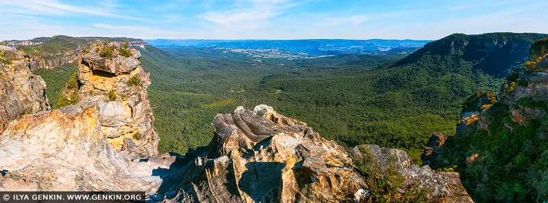 landscapes stock photography | Open Horizon, Megalong Valley, Blue Mountains National Park, NSW, Australia. Held beneath a clear blue sweep, the valley unfolds in vast layers of forest, sandstone and distant escarpment. Its immense openness brings a sense of release into a room - quieting the mind, restoring perspective and creating the feeling of standing at the edge of something timeless. As a commanding design anchor, the deep eucalyptus greens, sun-warmed stone and luminous blues introduce both grounded strength and expansive light to refined living spaces, private retreats or executive interiors. Presented in a large-format museum scale, the panoramic composition truly comes alive, extending the visual boundaries of the room and turning the wall into an open horizon.