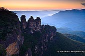 landscapes stock photography | The Three Sisters, Echo Point, Katoomba, Blue Mountains, NSW, Australia, Image ID THREE-SISTERS-BLUE-MOUNTAINS-0001. The Three Sisters towering above the Jamison Valley at Sunrise as it was seen from the Echo Point in Katoomba in Blue Mountains, NSW, Australia. The lighter coloured orange and yellow sections indicate fresh rock, exposed by recent erosion.