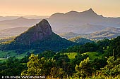 landscapes stock photography | Mount Warning at Sunset, The Northern Rivers, NSW, Australia, Image ID AU-MOUNT-WARNING-0001. Mount Warning (Aboriginal: Wollumbin), a mountain in the Tweed Range in the Northern Rivers region of New South Wales, Australia, was formed from a volcanic plug of the now-gone Tweed Volcano. The mountain is located 14 kilometres (9 mi) west-south-west of Murwillumbah, near the border between New South Wales and Queensland. Due to Mount Warning's proximity to Cape Byron, the Australian continent's easternmost point, it is the first place on mainland Australia to receive the sun's rays each day. Lieutenant James Cook saw the mountain from the sea and named it Mount Warning. He also named a bit of land jutting out of the shoreline as Point Danger (later known as Fingal Head). Together they were named as a point of reference to warn other explorers that came afterward.