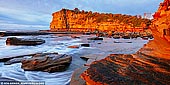 landscapes stock photography | The Skillion at Sunrise, Terrigal, Central Coast, NSW, Australia, Image ID SKILLION-TERRIGAL-0001. Terrigal is a popular residential, tourist and retirement centre with a bustling holiday ambience which is modified by the gracious Norfolk pines along The Esplanade, the pleasant beach front walkway which heads south to Broken Head, and the dominating natural feature known as 'The Skillion' which offers dramatic views up and down the coast. Visitors are attracted by the town's classy four and a half star hotel, the fishing, swimming, surfing, boating and the coastal scenery. Terrigal Beach is one of those glorious beaches which stretches, unbroken, for four kilometres and is known as Terrigal at the southern end and Wamberal at the northern end. The Skillion is the most prominent landmark of the region, with a steep cliff facing the ocean rising to a convenient lookout area that is easily accessed by a flat grassy area leading up from the reserve.