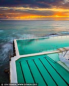 landscapes stock photography | Sunrise at Bondi Icebergs, Bondi Beach, Sydney, NSW, Australia, Image ID AU-BONDI-BEACH-0004. The Icebergs Bondi Baths have been a landmark of Bondi Beach for over 100 years. For more than a century, Tasman Sea waves have crashed against - and into - the Bondi Baths, an Olympic-size pool that became the home of the Bondi Icebergs, a winter swimming club, in 1929. Because of its solid concrete construction, the pool is always slightly colder than the ocean, even though it uses the same water. The public is welcome here, but locals who want to become Icebergs (i.e., earn their official stripes as winter swimmers) must log 75 swims here during what most would consider the 'off-season' (when pool temps dip below 15C in wintry July). Casual visitors favour summertime dips, when the water warms to the high 20s by February. Upon emerging from the striking shoreside pool at the Icebergs, bathers enjoy the amenities of its modernist, beachy clubhouse complex, which includes a gourmet bistro, two bars, fitness facilities and a 1,600-square-foot sundeck.