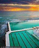 landscapes stock photography | Sunrise at Bondi Icebergs, Bondi Beach, Sydney, NSW, Australia, Image ID AU-BONDI-BEACH-0004. The Icebergs Bondi Baths have been a landmark of Bondi Beach for over 100 years. For more than a century, Tasman Sea waves have crashed against - and into - the Bondi Baths, an Olympic-size pool that became the home of the Bondi Icebergs, a winter swimming club, in 1929. Because of its solid concrete construction, the pool is always slightly colder than the ocean, even though it uses the same water. The public is welcome here, but locals who want to become Icebergs (i.e., earn their official stripes as winter swimmers) must log 75 swims here during what most would consider the 'off-season' (when pool temps dip below 15C in wintry July). Casual visitors favour summertime dips, when the water warms to the high 20s by February. Upon emerging from the striking shoreside pool at the Icebergs, bathers enjoy the amenities of its modernist, beachy clubhouse complex, which includes a gourmet bistro, two bars, fitness facilities and a 1,600-square-foot sundeck.