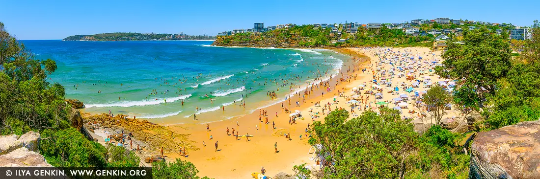 Golden Curve of Freshwater Bay - Fine art print of Sydney, NSW, Australia - From a lush headland vantage, Freshwater Beach unfurls in a radiant arc - its golden sands alive with the energy of summer. Beneath a sapphire sky, beachgoers fill every corner of this beloved Sydney cove, while out in the sparkling turquoise shallows, surfers and swimmers share the rhythm of the waves. Framed by rugged rock formations and coastal greenery, and backed by a hillside of modern residences, this sweeping panorama captures the joyous chaos of a perfect beach day. It's a vivid expression of coastal life - ideal for energising a living space, holiday home, or creative studio with warmth, vitality, and the spirit of the sea. - Image ID: AU-FRESHWATER-BEACH-0005