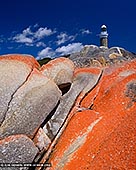 landscapes stock photography | Eddystone Point Lighthouse #2, Mount William National Park, Tasmania (TAS), Australia, Image ID TAS-EDDYSTONE-POINT-LIGHTHOUSE-0002. Photograph of the Eddystone Point Lighthouse with lichen covered rocks in foreground. On the far north-east of Tasmania, almost on the 41 st latitude, is the Eddystone Point Lighthouse. It is a magnificent circular stone 36 metre high tower, built of locally quarried granite and is situated on the headland known as Eddystone Point 41 metres above sea level. The light commenced operation on 1 May 1889. Eddystone Point LighthouseThe light was established because of nearby dangers in eastern Banks Strait and south along the coast known as the Bay of Fires. Georges Rocks, Victorias Rocks and Black Reef are amongst the more prominent dangers in the area.