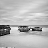 landscapes stock photography | The London Arch in Black and White, The Twelve Apostles, Great Ocean Road, Port Campbell National Park, Victoria, Australia, Image ID APOST-0033. London Arch (formerly London Bridge) is an offshore natural arch formation in the Port Campbell National Park, Australia. The arch is a significant tourist attraction along the Great Ocean Road near Port Campbell in Victoria. This stack was formed by a gradual process of erosion, and until 1990 formed a complete double-span natural bridge. The span closer to the shoreline collapsed unexpectedly on 15 January 1990, leaving two tourists (Kelli Harrison and David Darrington) stranded on the outer span before being rescued by police helicopter. No one was injured in the event. Prior to the collapse, the arch was known as London Bridge because of its similarity to its namesake.