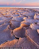 landscapes stock photography | Sunrise at Lake Eyre, Kati Thanda - Lake Eyre National Park, South Australia (SA), Australia, Image ID AU-LAKE-EYRE-0003. Lake Eyre is normally dry; it fills completely only an average of twice in a century, but partial, minor fillings happen much more often. When completely filled (as in 1950, 1974, and 1984), the lake takes about two years to dry up again. Lake Eyre is in a region of very low and intermittent rainfall amounting to less than 5 inches (125 mm) annually. The lake is fed by a vast internal continental drainage basin, but evaporation rates in the region are so high that most of the rivers in the basin dry up before reaching the lake. Thus, the waters of the Diamantina and other rivers can feed the lake only when they are in flood after heavy rains. The thin salt crust of Lake Eyre thickens in the lake's southern portions, where it is as much as 18 inches (46 cm) thick. The extremely level surface of the salt crust has been used in attempts to break world land-speed records, notably in 1964, when Donald Campbell drove at a speed of more than 400 miles (644 km) per hour in Bluebird II.