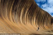 landscapes stock photography | Wave Rock, Hyden, Western Australia, Image ID WA-WAVE-ROCK-0001. Wave Rock is one of the many amazing rock formations found in Western Australia. It is situated near the small town of Hyden, about 350km east of Perth. Wave Rock stands 15m high, 100m long and looks like a tall wave just about to break. This unusual shape has been greatly highlighted by vertical streaks of algae which grow on the surface of the 'wave' as dark black stains which change to brown during the dry season. The shape of the wave is formed by gradual erosion of the softer rock beneath the upper edge, over many centuries. Also, in the Wave Rock Area are other unusual rocky outcrops such as Hippos Yawn, The Humps, Camel Peaks, King Rocks. These are the largest and most well known and are but a few of hundreds that are scattered around this central wheat belt area. This photo is actually the perfect example of why you need to shoot people in landscape photos sometimes – just to get depth and scale.