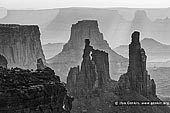 landscapes stock photography | Washer Woman Arch, Monster Tower and Airport Tower, Island in the Sky, Canyonlands National Park, Utah, USA, Image ID CANYONLANDS-NATIONAL-PARK-UTAH-USA-0006. Washer Woman Arch, Monster Tower and Airport Tower cast shadows on haze in the air at sunrise in the Island in the Sky district of Canyonlands National Park, Utah, USA. Washer Woman Arch resembles a woman washing clothes on an old-fashioned washboard. The Washer Woman Arch is in silhouette in front of the Airport Tower and the Monster Tower is immediately on the right.