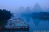landscapes stock photography | Early Morning on Li River Near Yangshuo, Yangshuo, China, Image ID CHINA-YANGSHUO-XINGPING-0005. A picture of early misty morning on Li River (Lijiang River) near Yangshuo city in Guangxi province in China. Recreational cruise boats awaiting tourists for cruises on crystal-clear waters of Li River that twists and turns between magnificent and beautiful carst mountains.