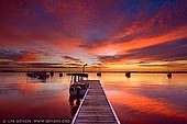 Sunrise at Wangi Point Jetty - Fine art print of Wangi Wangi, Lake Macquarie, NSW, Australia - Beautiful image of dramatic sunrise over the Lake Macquarie at Wangi Point Jetty in NSW, Australia. The sky was in all hues from red, purple, orange and yellow turning the entire scene into magical place. Sunrises can be a magical time of day, especially when the sunrise is so amazing, such as the one captured here. The reason that the sunrise contains such vibrant yellow and red colours in this photo is due to the way that the sun is dispersing the thunder clouds forming over the region. Depending on what particles are in the air, sunrise can be any number of colours, but if you have a trained eye, you can tell what is happening in the sky by what colour it turns as the sun is rising. - Image ID: AU-LAKE-MACQUARIE-0001