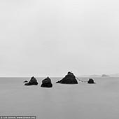 portfolio stock photography | Meoto Iwa #2 (The Wedded Rocks), Futami, Mie Prefecture, Japan, Image ID JAPAN-MEOTO-IWA-0002. Meoto Iwa or the Married Couple Rocks, are two rocky stacks in the sea off Futami, Mie, Japan. They are joined by a shimenawa (a heavy rope of rice straw) and are considered sacred by worshippers at the neighboring Futami Okitama Shrine (Futami Okitama Jinja). According to Shinto, the rocks represent the union of the creator of kami, Izanagi and Izanami. The rocks, therefore, celebrate the union in marriage of man and woman. The rope, which weighs over a ton, must be replaced several times a year in a special ceremony. The larger rock, said to be male, has a small torii at its peak.