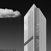 Monolith in the Sky - Gateway Tower in Black & White - Fine art print of Sydney, NSW, Australia - Poised beneath a solitary cloud and bathed in stark monochrome, the Gateway Tower rises like a minimalist sculpture against the Sydney skyline. This black-and-white portrait strips the scene to its essential contrasts - light, form, and shadow - revealing the building's austere elegance and geometric precision. The quiet drama of a single cloud drifting beside the tower adds a surreal softness to the composition, balancing the rigid lines with a fleeting sense of movement. In this abstraction, the skyscraper becomes both modern temple and urban sentinel - a striking statement piece for interiors that favour clean lines, bold contrast, and architectural grace. - Image ID: SYDNEY-IN-SQUARE-0028