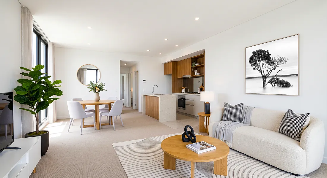 Modern Australian apartment living room with neutral sofa, timber kitchen, dining area and black and white coastal wall art above the couch