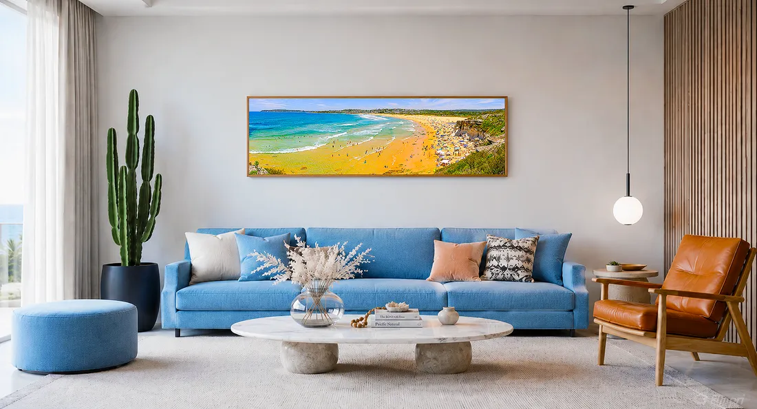 Bright contemporary living room in a luxury home with a blue sofa and a large panoramic beach artwork hung above it.