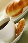 Fresh-baked croissant, cookies and cup of coffee. Shallow DOF. Focus on cup and cookies.